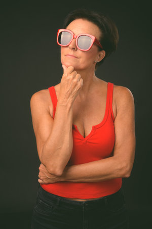 Mature beautiful woman with short hair against black backgroundの写真素材