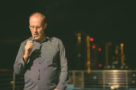 Mature man smoking electronic cigarette on the rooftop swimming poolの写真素材