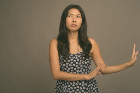 Asian woman wearing blue dress against gray background