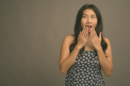 Asian woman wearing blue dress against gray backgroundの写真素材