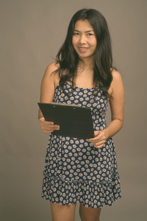 Asian woman wearing blue dress against gray backgroundの写真素材