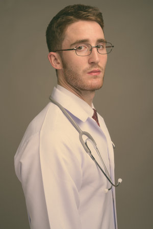 Young handsome man doctor wearing eyeglasses against gray backgroundの写真素材