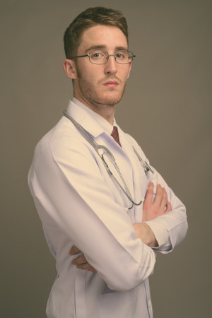 Young handsome man doctor wearing eyeglasses against gray backgroundの写真素材