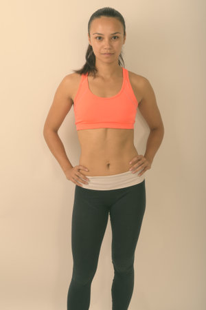 Studio shot of young Asian woman standing ready for gym against white backgroundの写真素材