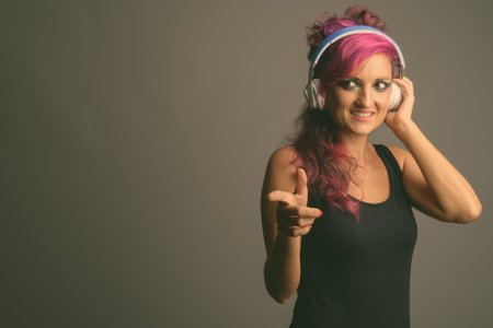 Beautiful woman with pink hair and make-up against gray backgroundの写真素材