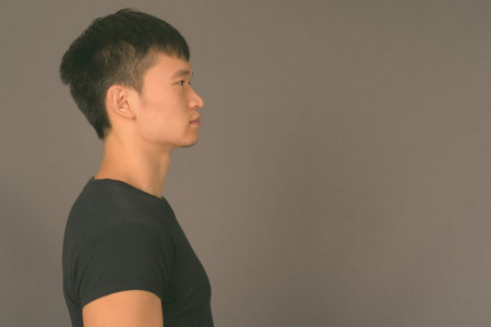 Studio shot of young Chinese man against gray background
