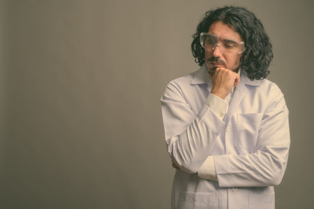 Handsome man doctor with mustache wearing protective glasses against gray background