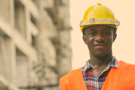 Young happy black African man construction worker smiling at building site