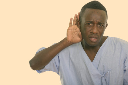 Studio shot of young black African man patient listening