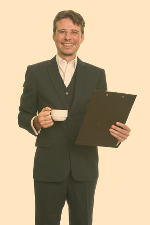 Happy Caucasian businessman holding clipboard and coffee cupの写真素材