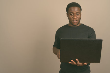 Young African man wearing black shirt against gray backgroundの写真素材