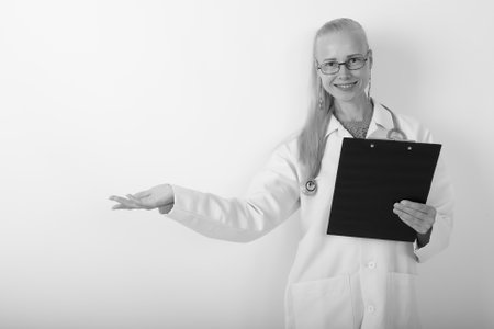 Beautiful blond woman doctor wearing eyeglasses against white backgroundの写真素材