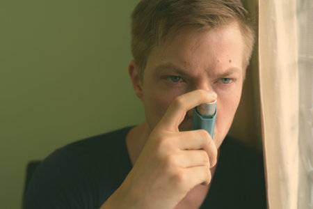 Young handsome man using asthma inhaler at homeの写真素材