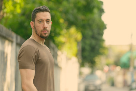 Young handsome Caucasian man looking at camera outdoors