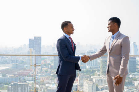 Portrait of two African businessman smiling and having handshake at rooftopの写真素材