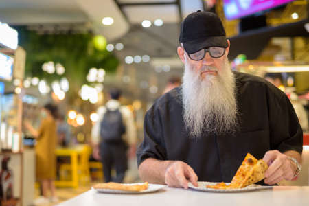 Man sitting in shopping mall and eating pizzaの写真素材