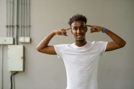 Portrait of handsome black African man with stressed attitude against plain wall backgroundの写真素材