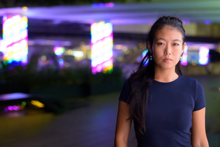Portrait of beautiful Asian woman outdoors at night
