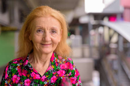 Portrait of a senior woman with blonde hair outdoors during summerの写真素材