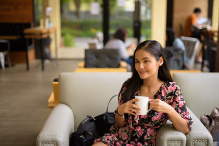 Portrait of beautiful Asian woman sitting and thinking at coffee shopの写真素材