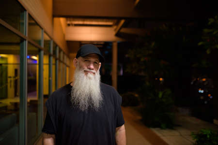 Portrait of mature man with gray beard outdoors at nightの写真素材