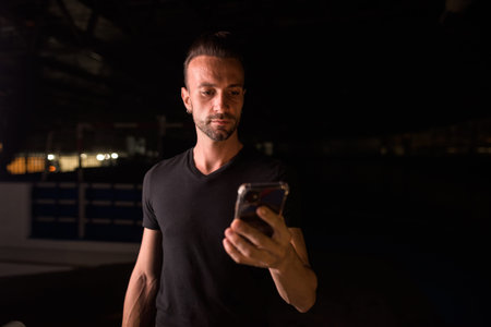 Man at night in parking lot building using mobile phone