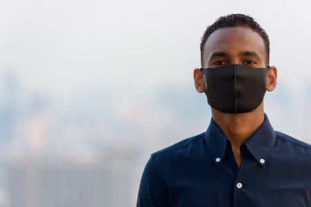 Portrait of handsome African businessman outdoors at rooftop in Bangkok, Thailandの写真素材