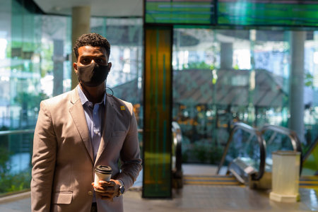 Portrait of handsome young African businessman wearing suit and face maskの写真素材