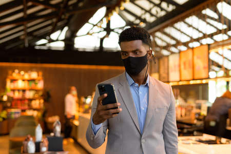 Portrait of handsome young African businessman wearing suit and face maskの写真素材