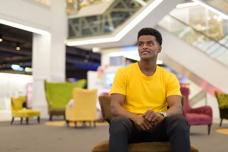 Portrait of handsome black African man wearing yellow t-shirt indoors