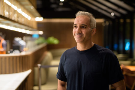 Portrait of man inside coffee shop at night smiling and thinking horizontal shot