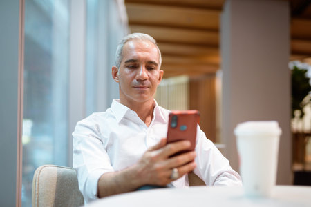 Portrait of handsome businessman sitting at coffee shop horizontal shotの写真素材