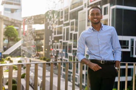 Portrait of handsome black African businessman outdoors in city during summerの写真素材