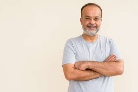 Portrait of happy bearded Indian man smiling against plain wallの写真素材