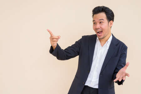 Portrait of Asian businessman wearing suit outdoors against plain backgroundの写真素材