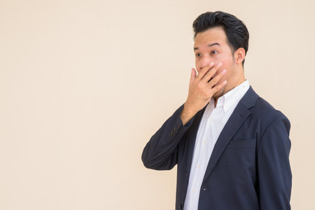 Portrait of Asian businessman wearing suit outdoors against plain backgroundの写真素材