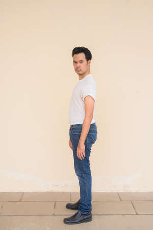 Portrait of Asian man wearing casual white t-shirt against plain background outdoorsの写真素材