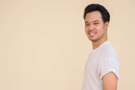 Portrait of Asian man wearing casual white t-shirt against plain background outdoorsの写真素材