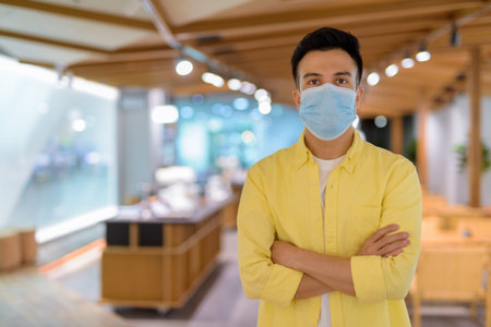 Portrait of handsome young man at coffee shop wearing face mask