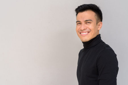Portrait of handsome young man against gray background smiling