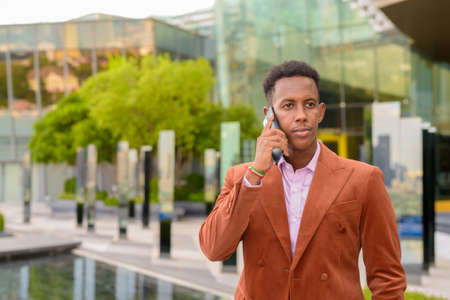 Portrait African businessman outdoors using mobile phone and wearing stylish clothesの写真素材