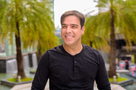 Portrait of Persian man outdoors in city during summer smiling and thinkingの写真素材