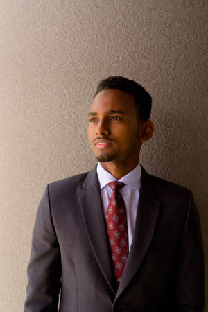 Portrait of African businessman wearing suit and tie outdoors in city while thinkingの写真素材
