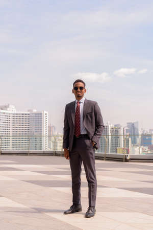 Full length portrait of African businessman wearing suit and tie outdoors in city while standingの写真素材
