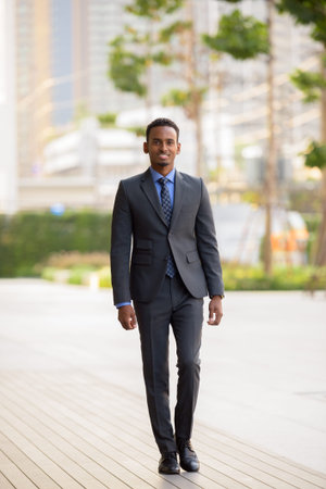 Handsome young African businessman wearing suit in cityの写真素材