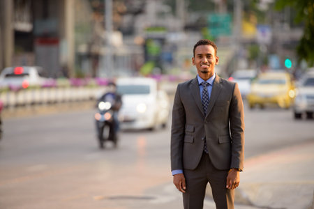 Handsome young African businessman wearing suit in city