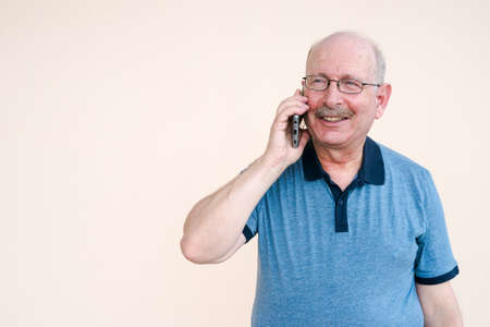Portrait of happy senior man using mobile phone while talkingの写真素材