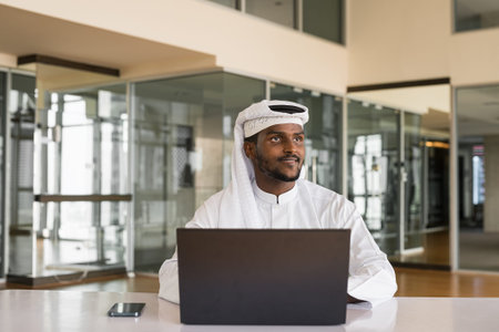 African Muslim man using laptop computer at office