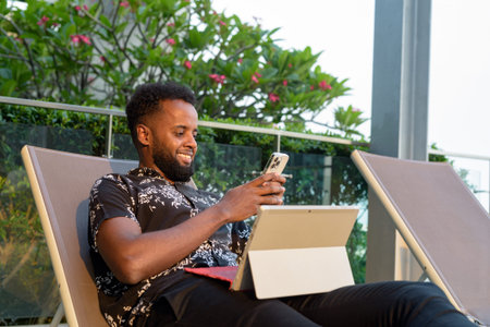 Portrait of handsome young African man outdoors using mobile phone