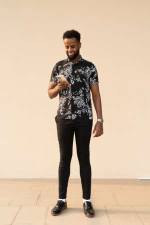 Portrait of handsome young African man outdoors using mobile phoneの写真素材